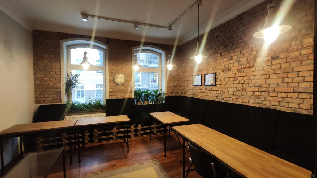 Sala Prestige Lingua w Gdańsku — ceglana ściana, drewniane stoły, lampy nad blatem
